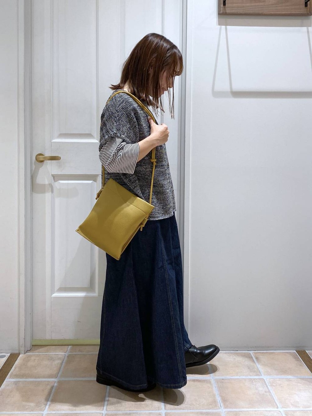 ブルー系のデニムパンツ、ブラック系のドレスシューズ、イエロー系のショルダーバッグを着用したレディースの夏コーディネートの7枚目の写真