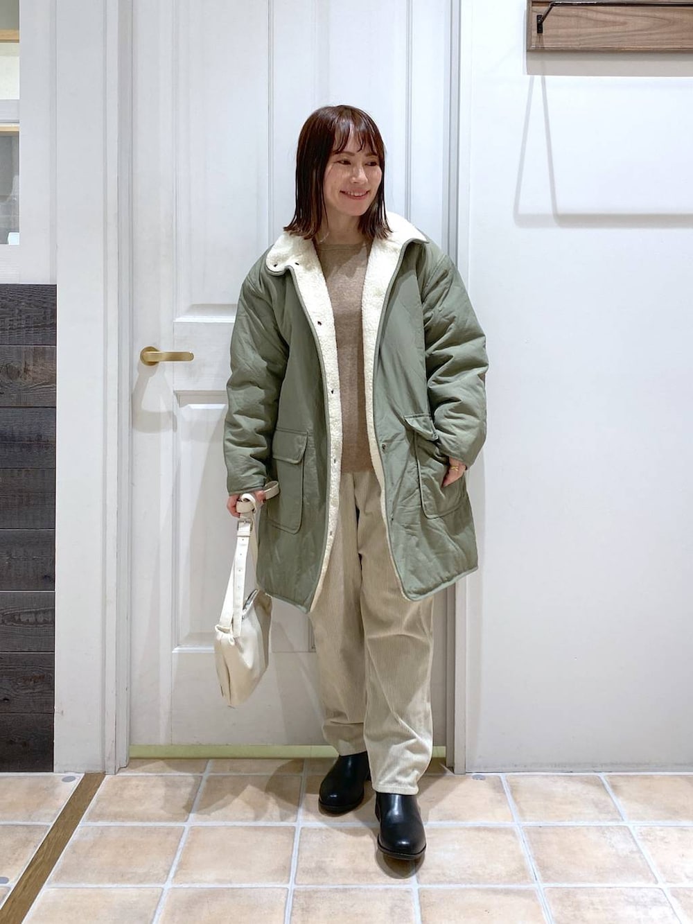 グリーン系のその他アウター、ブラック系のブーツ、グレー系のその他パンツを着用したレディースの冬コーディネートの3枚目の写真