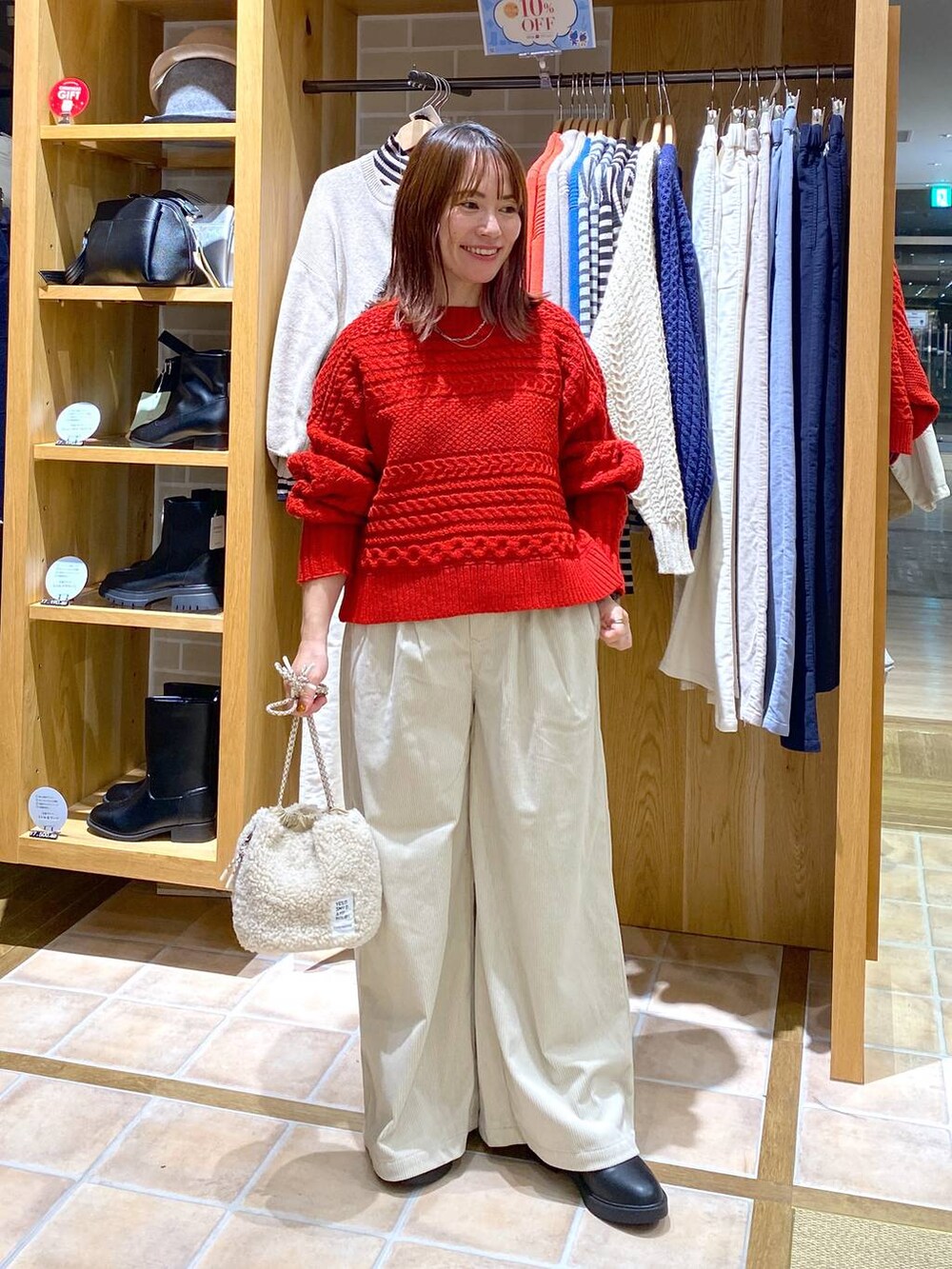 ブラック系のブーツ、ベージュ系のハンドバッグ、シルバー系のネックレスを着用したレディースの秋コーディネートの2枚目の写真