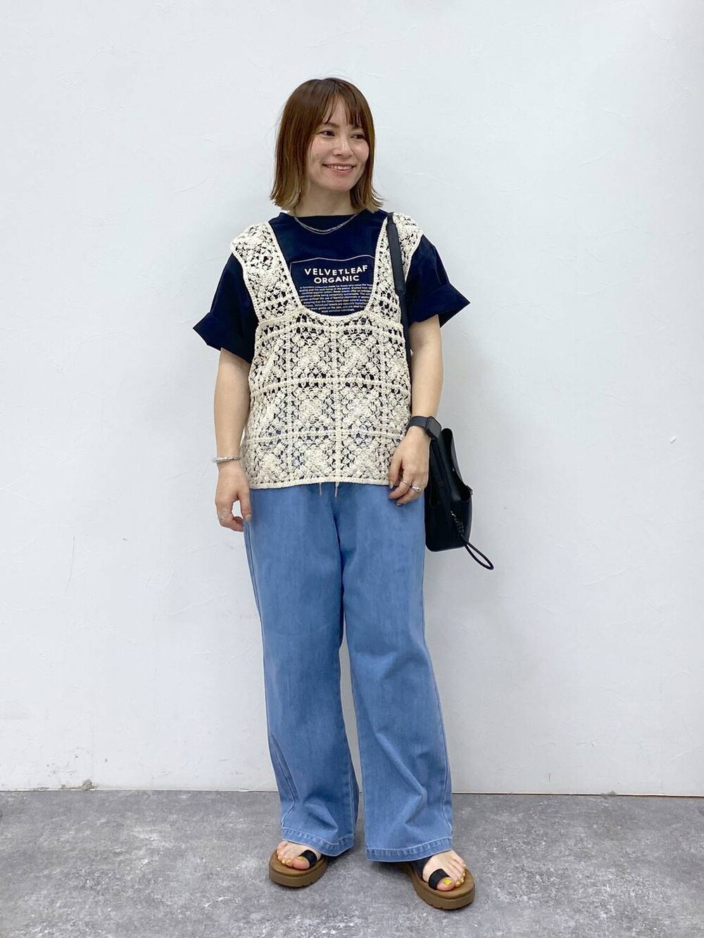 ブラック系のサンダル、ブルー系のデニムパンツ、ブラック系のショルダーバッグを着用したレディースの春コーディネートの2枚目の写真