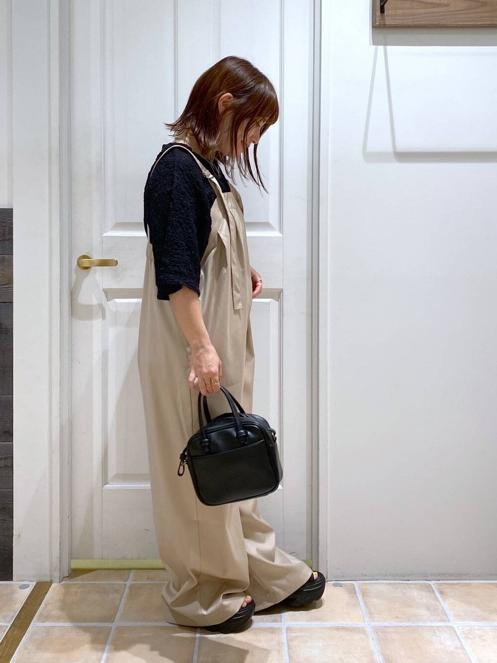 ブラック系のショルダーバッグ、ブラック系のサンダル、ブラック系のTシャツ/カットソーを着用したレディースの秋コーディネートの5枚目の写真