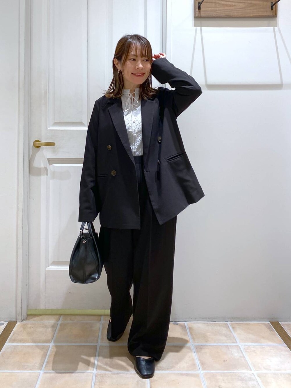 ブラック系のパンプス、ブラック系のスラックス、ブラック系のショルダーバッグを着用したレディースの冬コーディネートの2枚目の写真