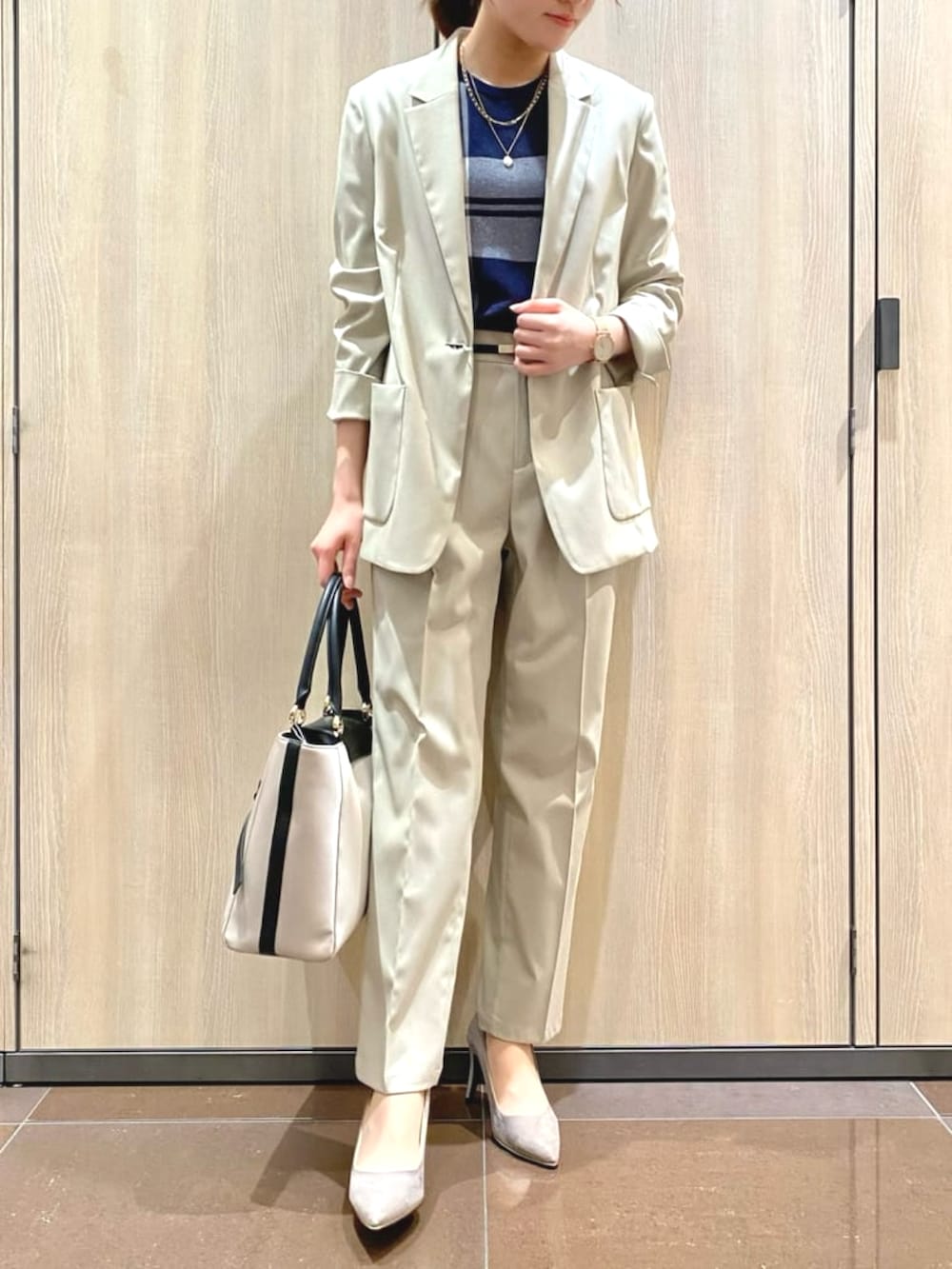 ブルー系のニット/セーター、ベージュ系のテーラードジャケット、ベージュ系のその他パンツを着用したレディースの夏コーディネートの2枚目の写真