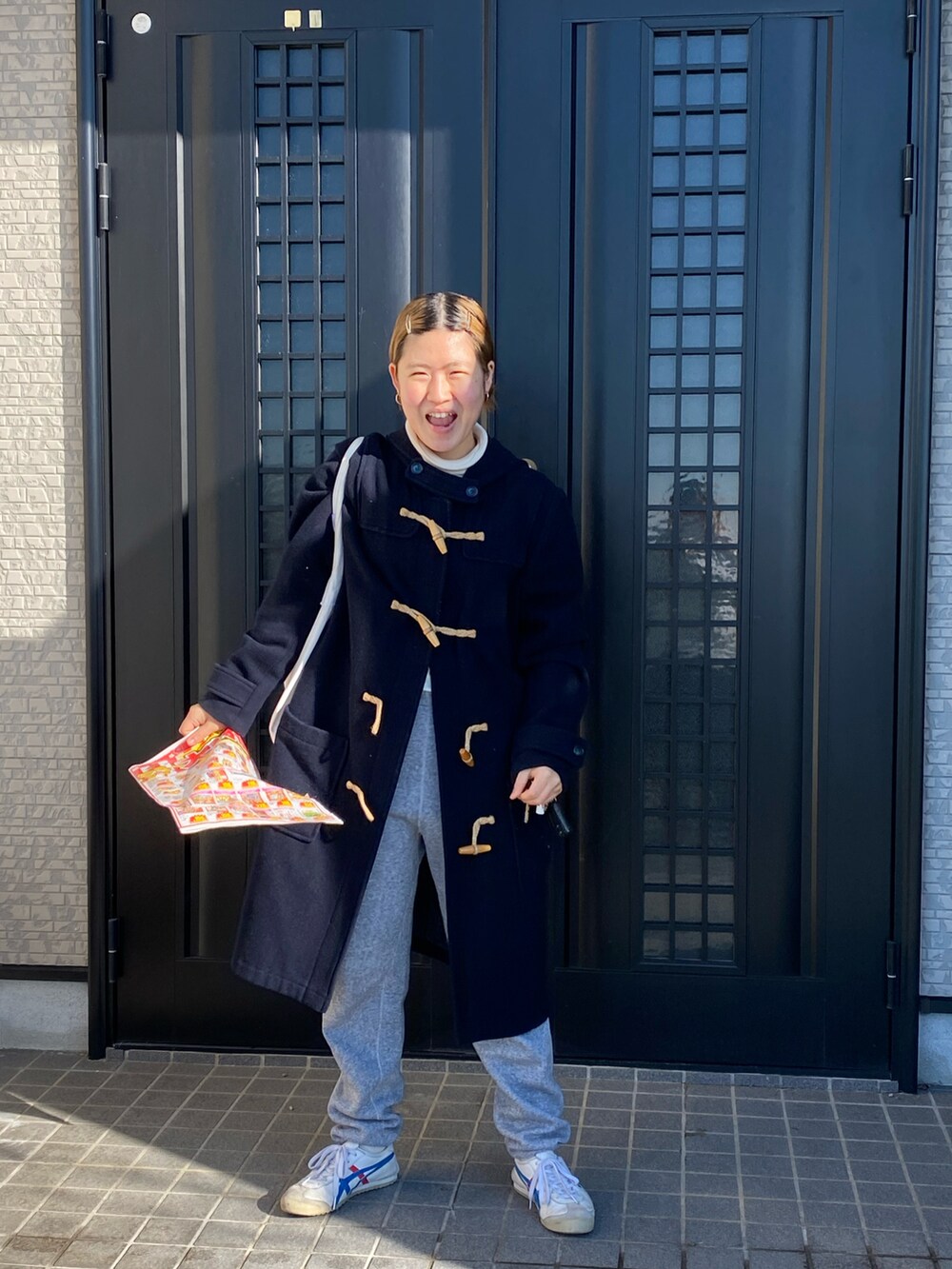 グレー系のスウェットパンツ、ホワイト系のスニーカー、ブルー系のダッフルコートを着用したレディースの冬コーディネートの3枚目の写真