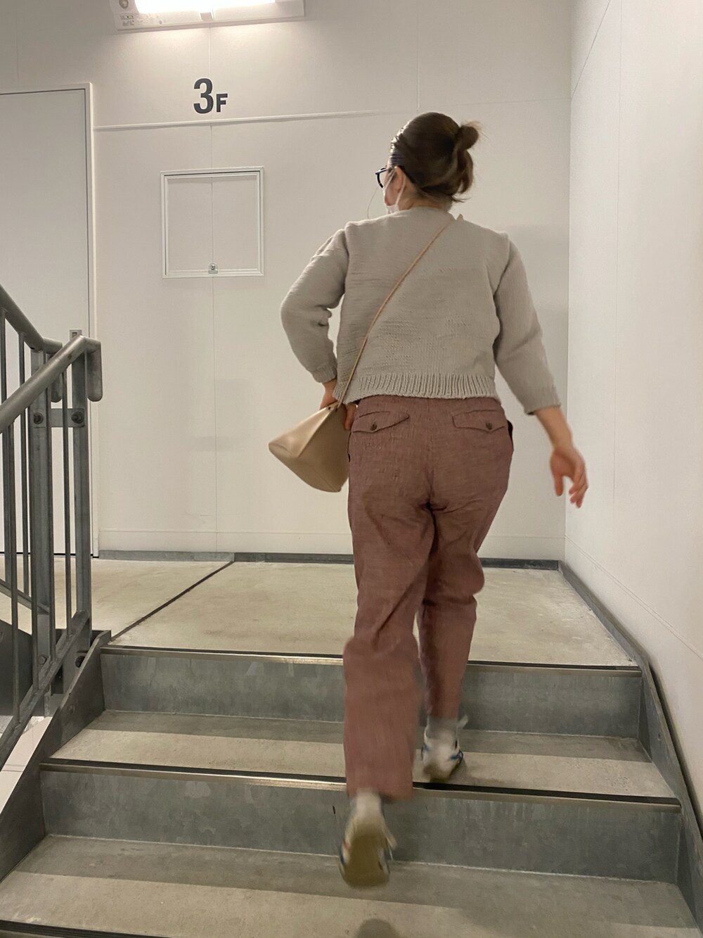 グレー系のニット/セーター、レッド系のスラックス、ホワイト系のスニーカーを着用したレディースの春コーディネートの2枚目の写真