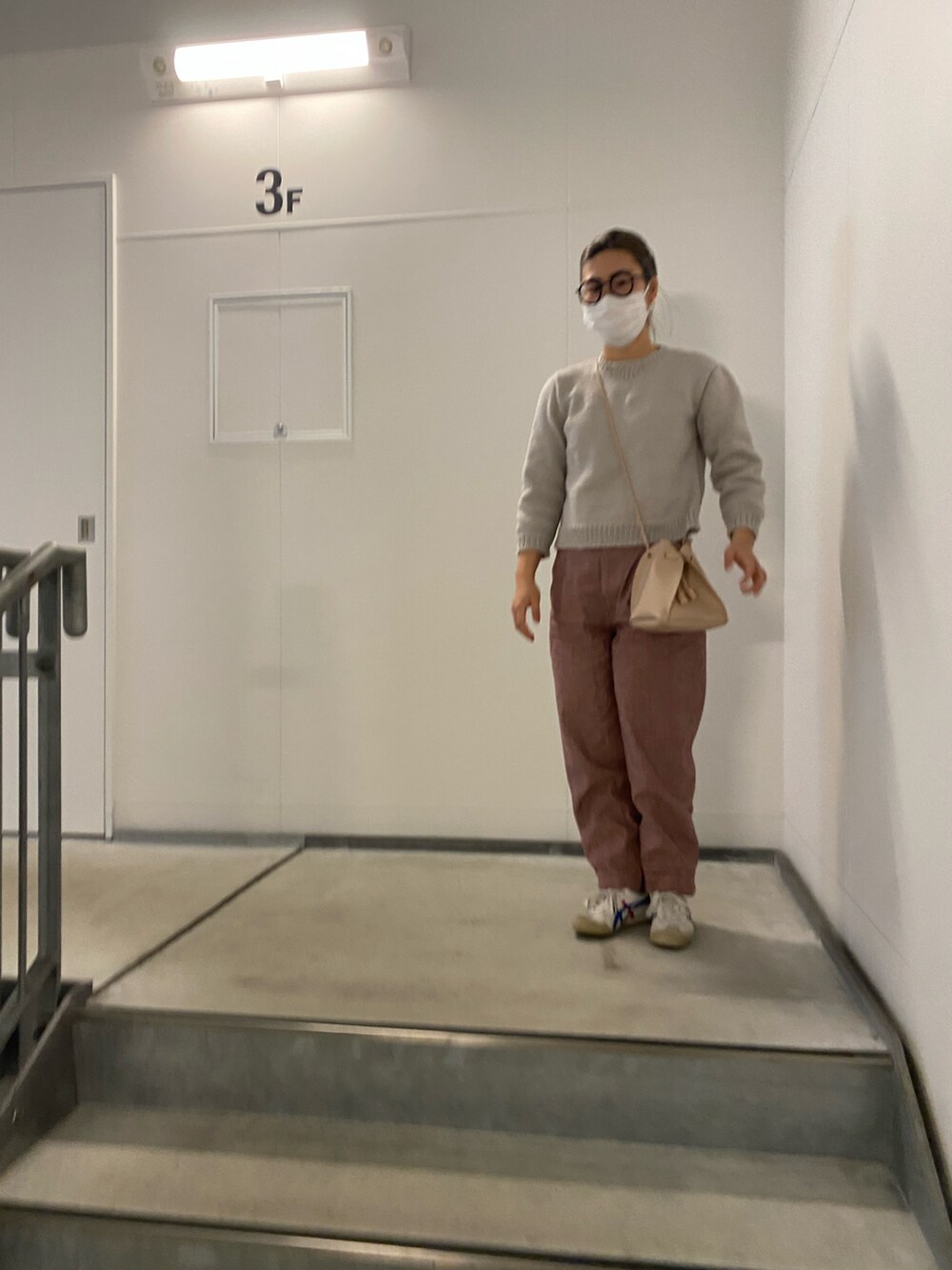 グレー系のニット/セーター、レッド系のスラックス、ホワイト系のスニーカーを着用したレディースの春コーディネートの3枚目の写真