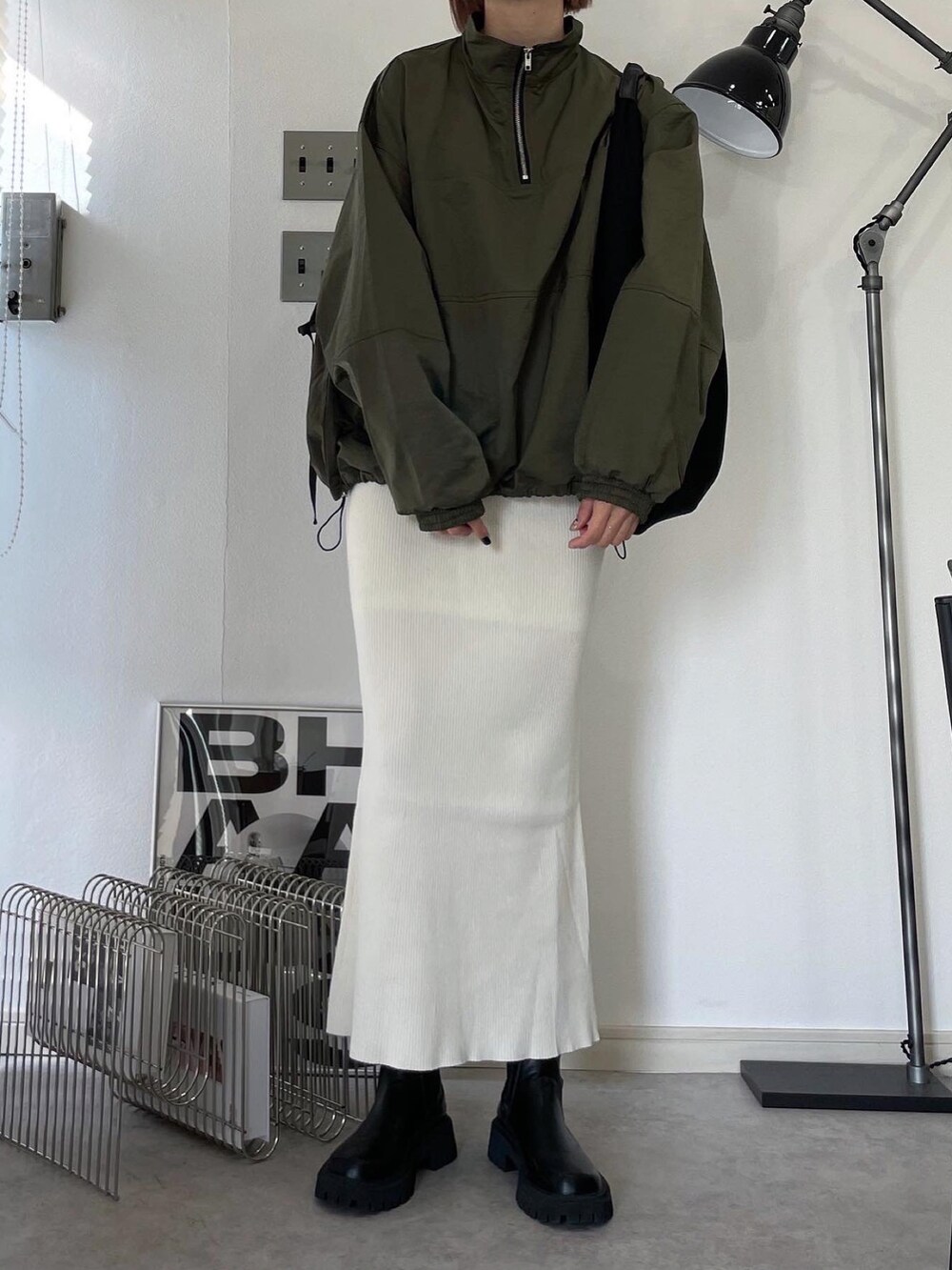 グリーン系のその他アウター、ホワイト系のスカート、ブラック系のブーツを着用したレディースの秋コーディネートの2枚目の写真