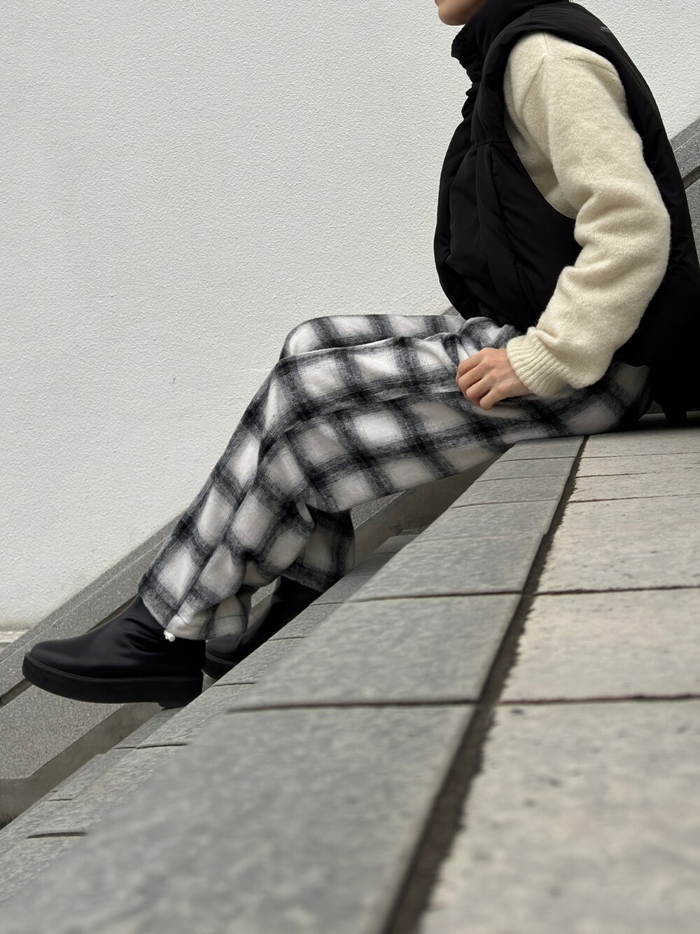 ホワイト系のニット/セーター、ホワイト系のその他パンツ、ブラック系のブーツを着用したレディースの冬コーディネートの2枚目の写真