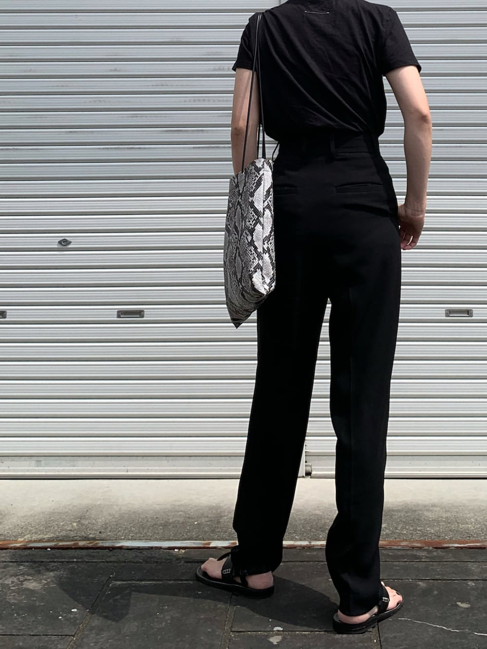 ブラック系のTシャツ/カットソー、ブラック系のスラックス、ブラック系のサンダルを着用したレディースの夏コーディネートの2枚目の写真