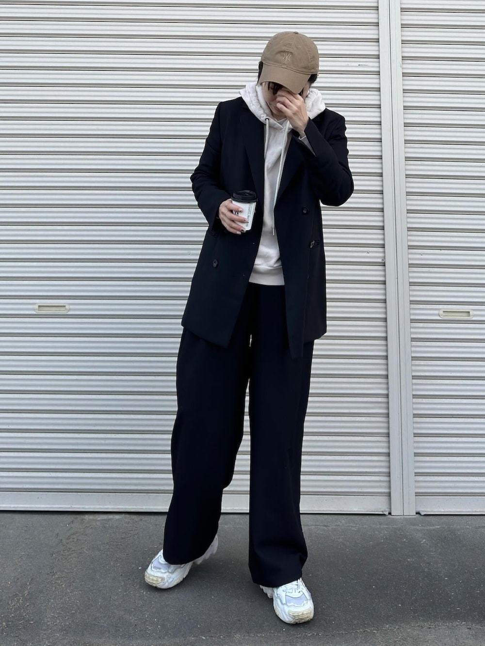 ブラック系のスラックス、ブラック系のスニーカー、ブラック系のテーラードジャケットを着用したレディースの冬コーディネートの2枚目の写真