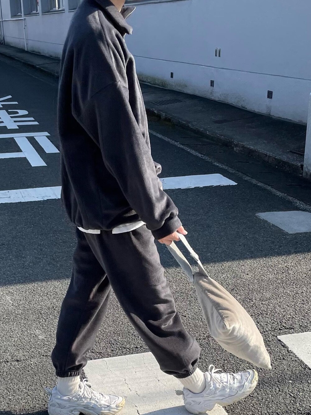 グレー系のセットアップ、ホワイト系のスニーカー、シルバー系のハンドバッグを着用したレディースの冬コーディネートの3枚目の写真