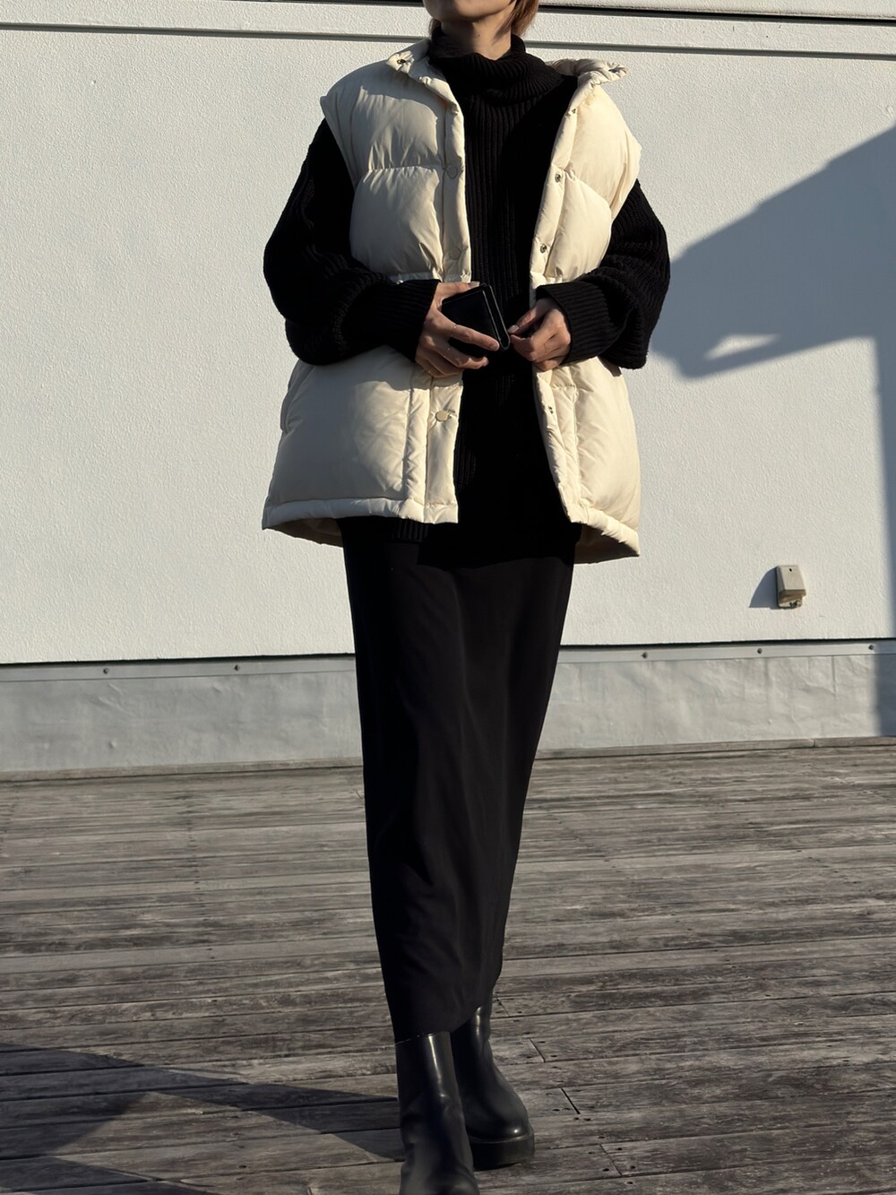 ホワイト系のダウンベスト、ブラック系のニット/セーター、ブラック系のスカートを着用したレディースの冬コーディネートの3枚目の写真