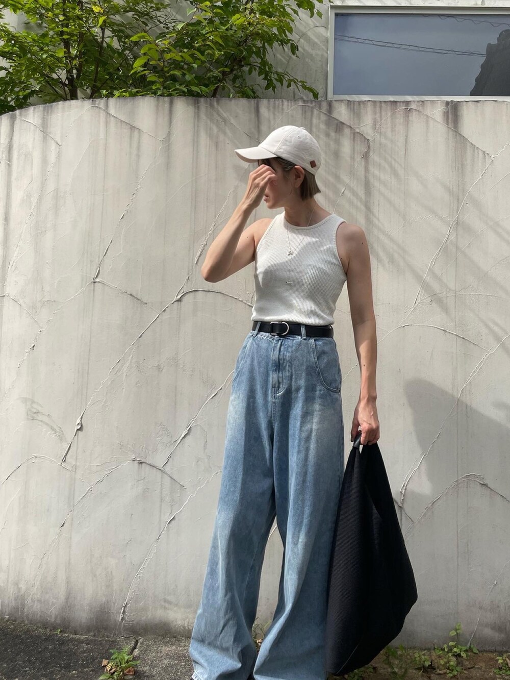 ホワイト系のタンクトップ、ブルー系のデニムパンツ、ブラック系のサンダルを着用したレディースの秋コーディネートの2枚目の写真