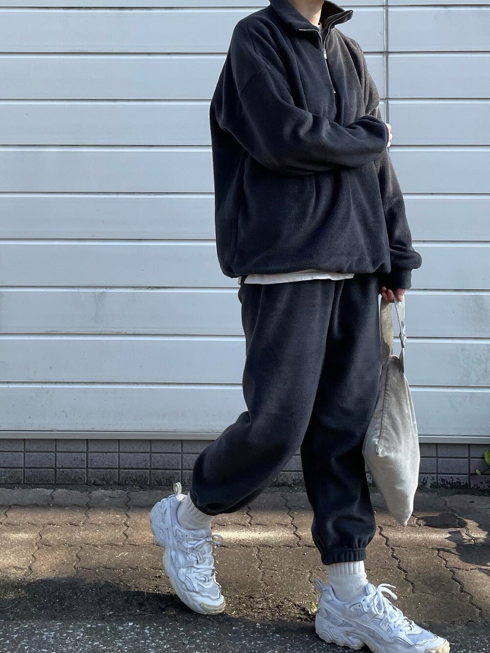 グレー系のセットアップ、ホワイト系のスニーカー、シルバー系のハンドバッグを着用したレディースの冬コーディネートの4枚目の写真