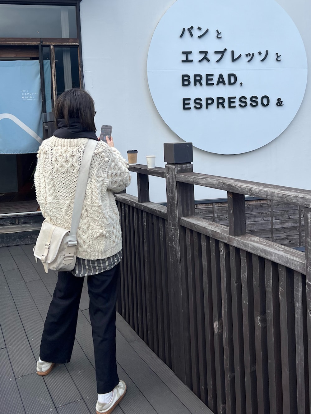 ホワイト系のニット/セーター、グレー系のシャツ/ブラウス、ホワイト系のスニーカーを着用したレディースの冬コーディネートの2枚目の写真