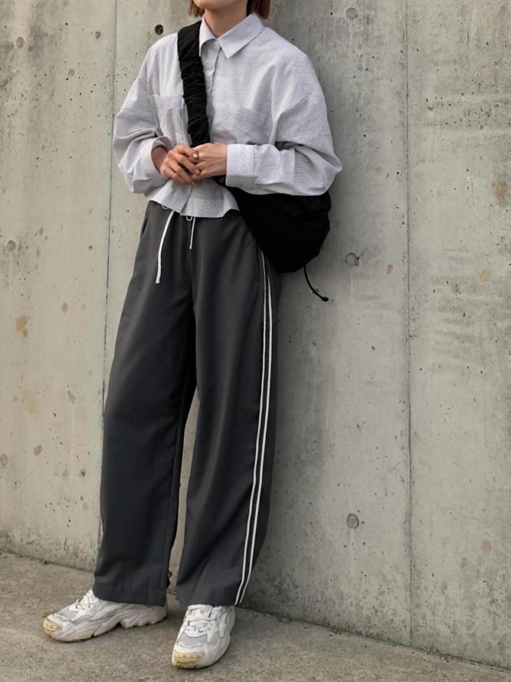 ブルー系のシャツ/ブラウス、グレー系のその他パンツ、ブラック系のショルダーバッグを着用したレディースの春コーディネートの2枚目の写真