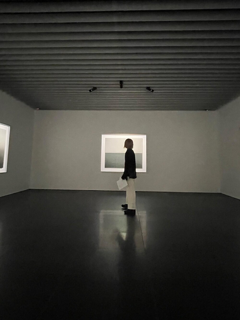 ブラック系のシャツ/ブラウス、ベージュ系のスラックス、ブラック系のブーツを着用したレディースの春コーディネートの2枚目の写真