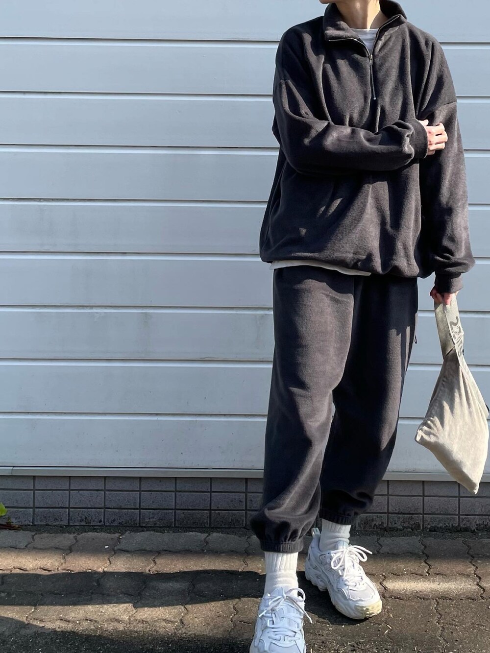 グレー系のセットアップ、ホワイト系のスニーカー、シルバー系のハンドバッグを着用したレディースの冬コーディネートの2枚目の写真