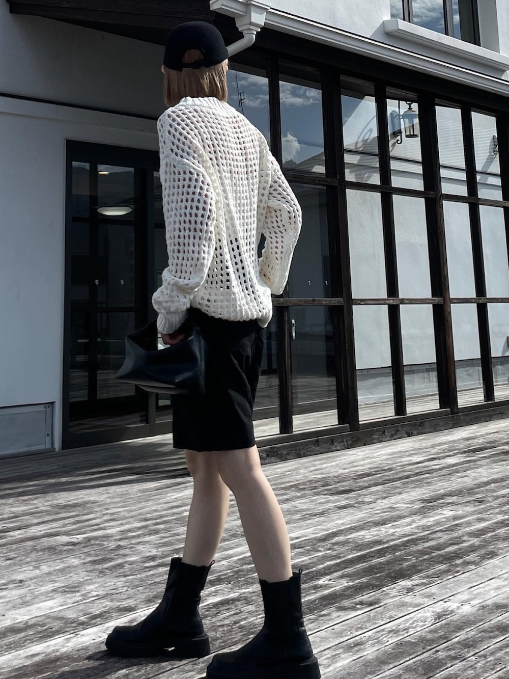 ホワイト系のニット/セーター、ブラック系のその他パンツ、ブラック系のブーツを着用したレディースの秋コーディネートの2枚目の写真