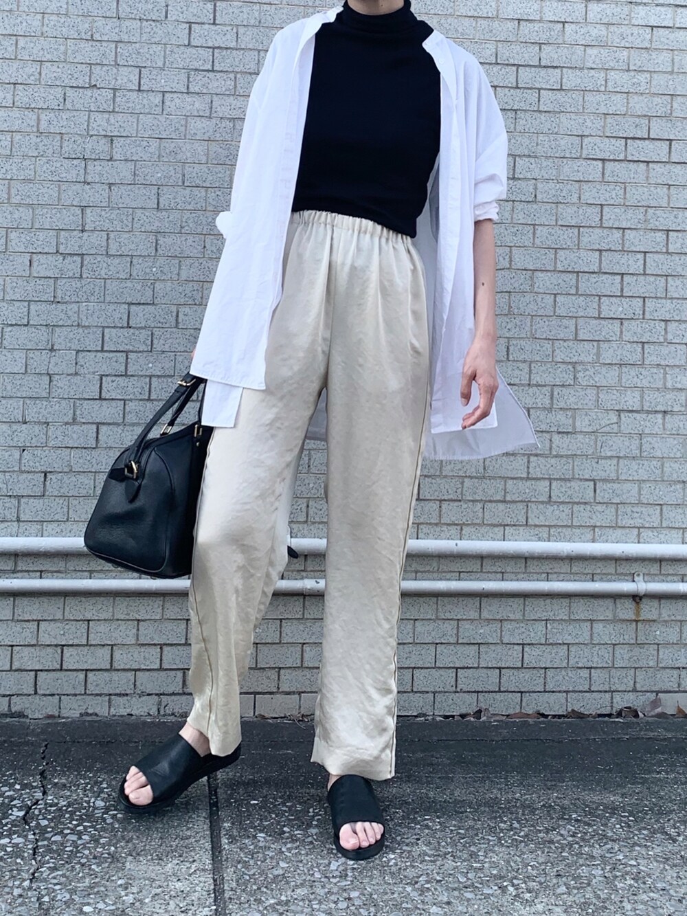 ブラック系のTシャツ/カットソー、ブラック系のサンダル、ホワイト系のその他パンツを着用したレディースの春コーディネートの2枚目の写真