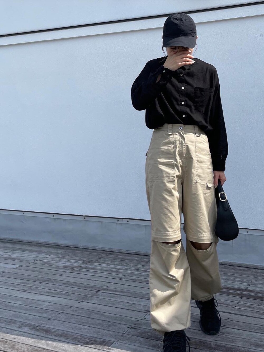 ブラック系のシャツ/ブラウス、ベージュ系のチノパンツ、ブラック系のスニーカーを着用したレディースの夏コーディネートの3枚目の写真
