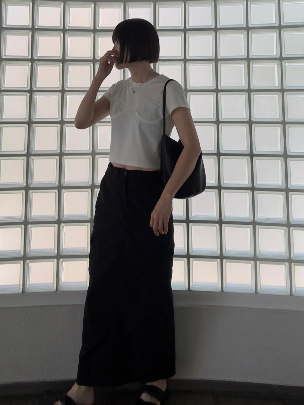 グリーン系のスカート、ブラック系のサンダル、ブラック系のバッグを着用したレディースの夏コーディネートの2枚目の写真