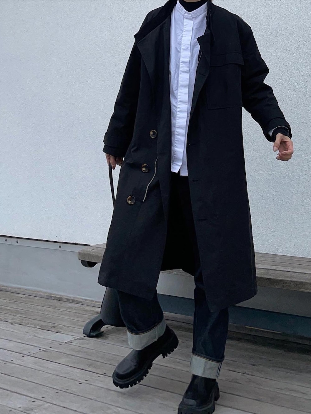 ブラック系のトレンチコート、ブルー系のデニムパンツ、ブラック系のブーツを着用したレディースの冬コーディネートの2枚目の写真