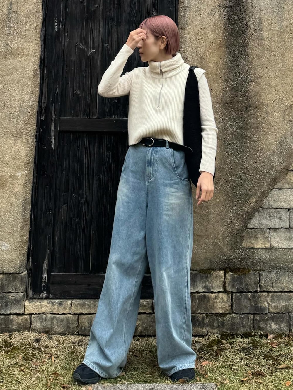 ホワイト系のベスト、ブラック系のトートバッグ、ブルー系のデニムパンツを着用したレディースの秋コーディネートの2枚目の写真