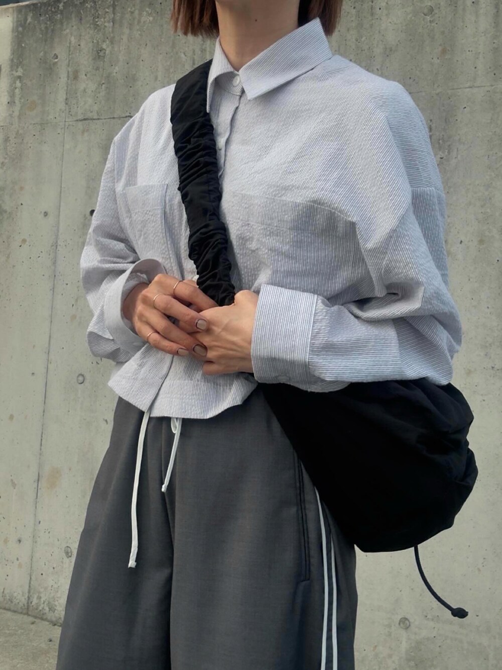 ブルー系のシャツ/ブラウス、グレー系のその他パンツ、ブラック系のショルダーバッグを着用したレディースの春コーディネートの3枚目の写真