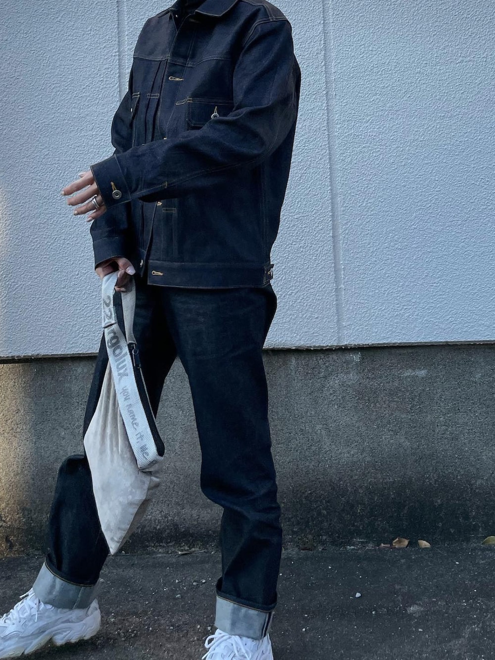 ブルー系のデニムジャケット、ブルー系のデニムパンツ、シルバー系のハンドバッグを着用したレディースの冬コーディネートの4枚目の写真