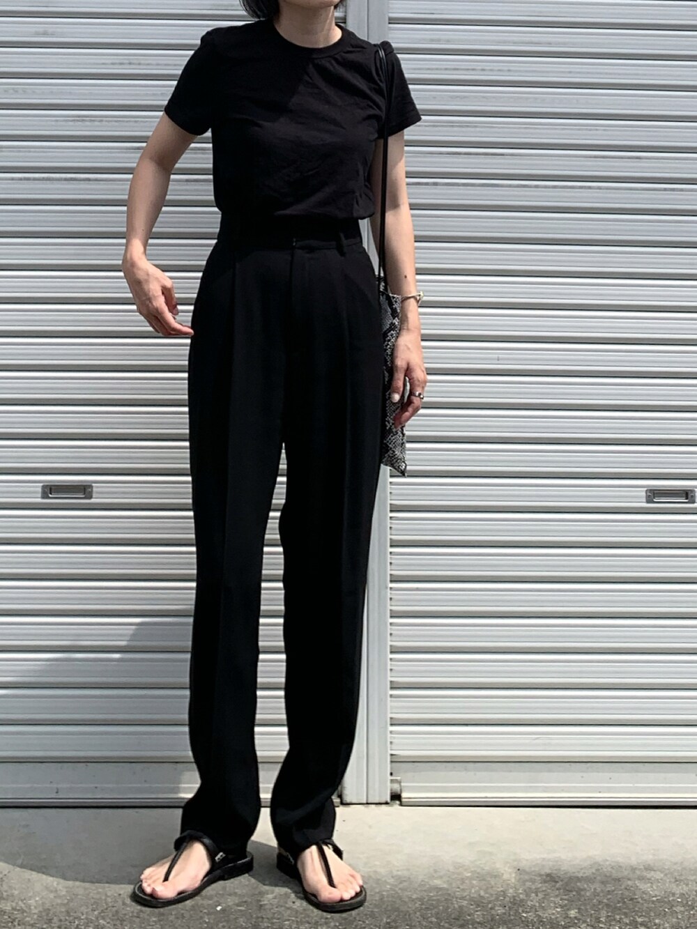 ブラック系のTシャツ/カットソー、ブラック系のスラックス、ブラック系のサンダルを着用したレディースの夏コーディネートの4枚目の写真