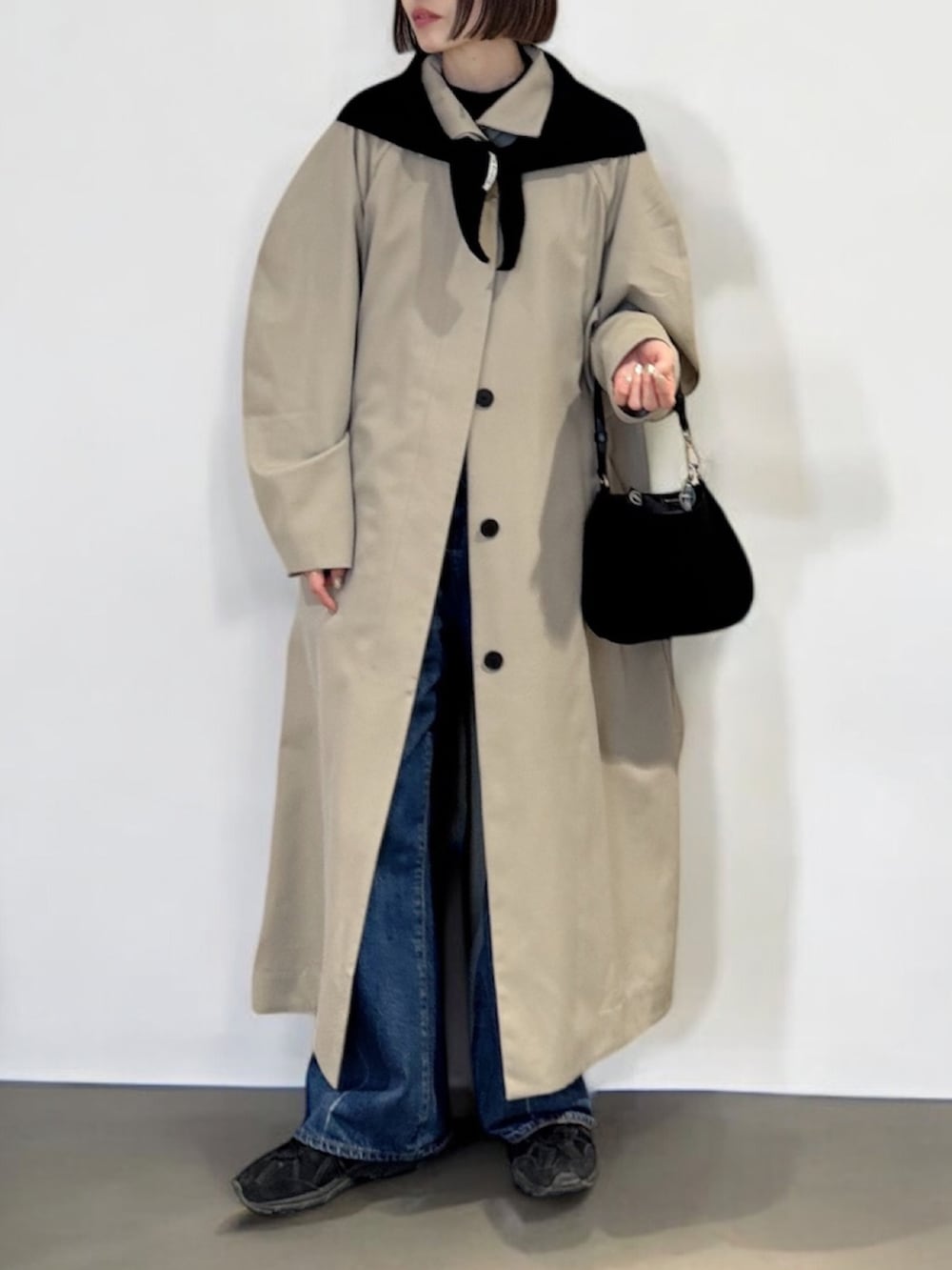 ベージュ系のトレンチコート、ブルー系のデニムパンツ、ブラック系のスニーカーを着用したレディースの冬コーディネートの2枚目の写真