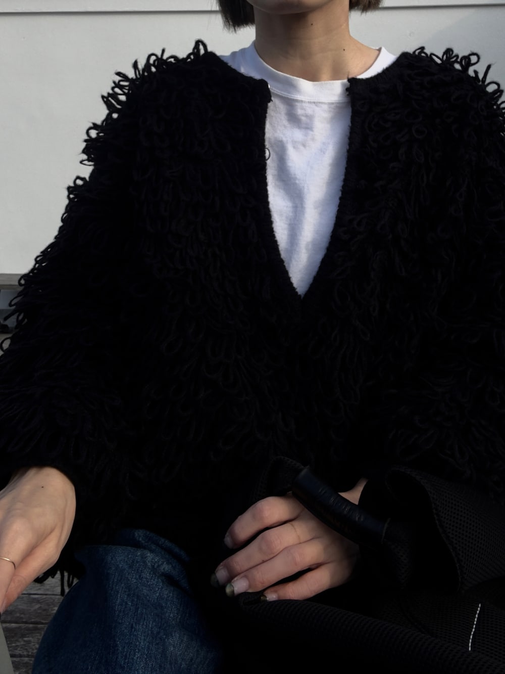 ブルー系のデニムパンツ、ブラック系のトートバッグ、ブラック系のニット/セーターを着用したレディースの冬コーディネートの2枚目の写真