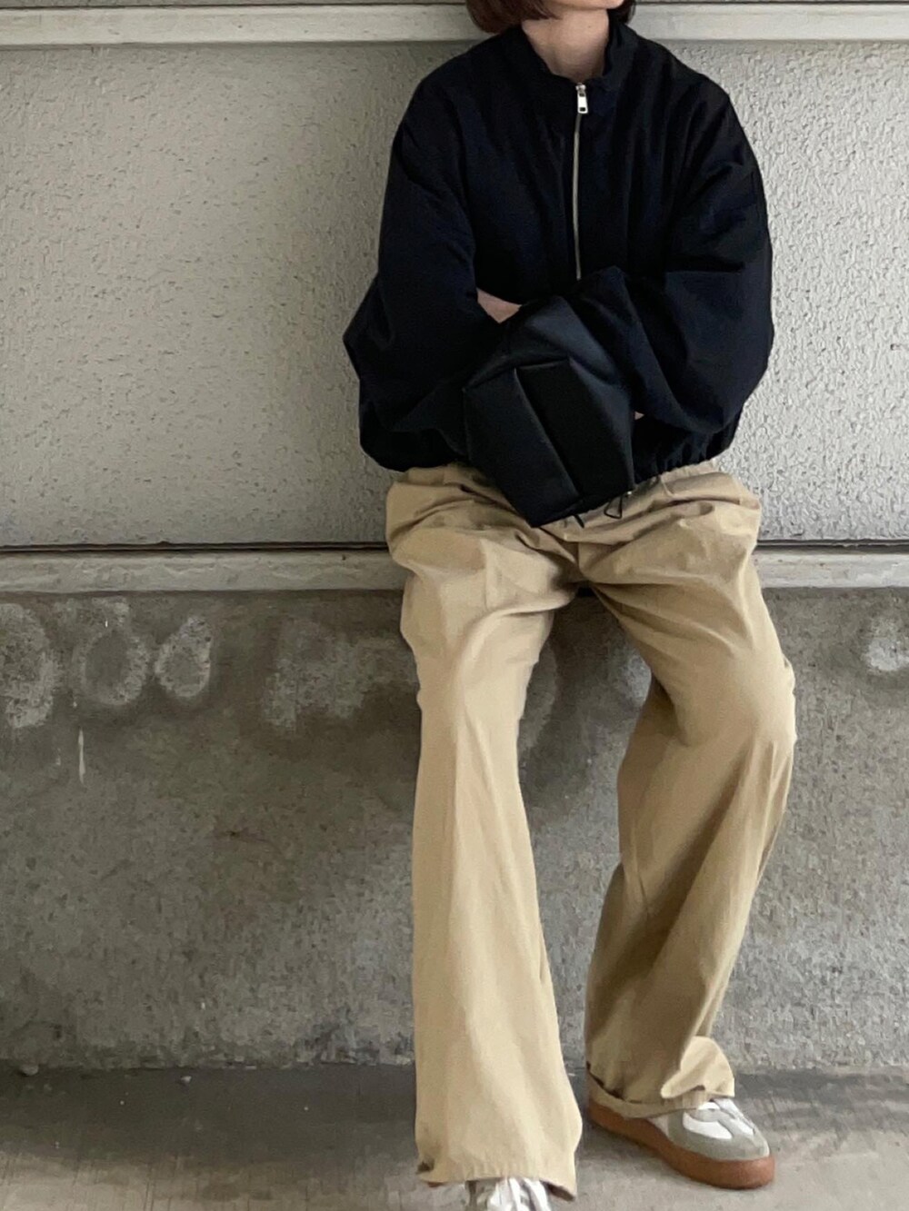 ブラック系のブルゾン、ベージュ系のその他パンツ、ホワイト系のスニーカーを着用したレディースの春コーディネートの3枚目の写真