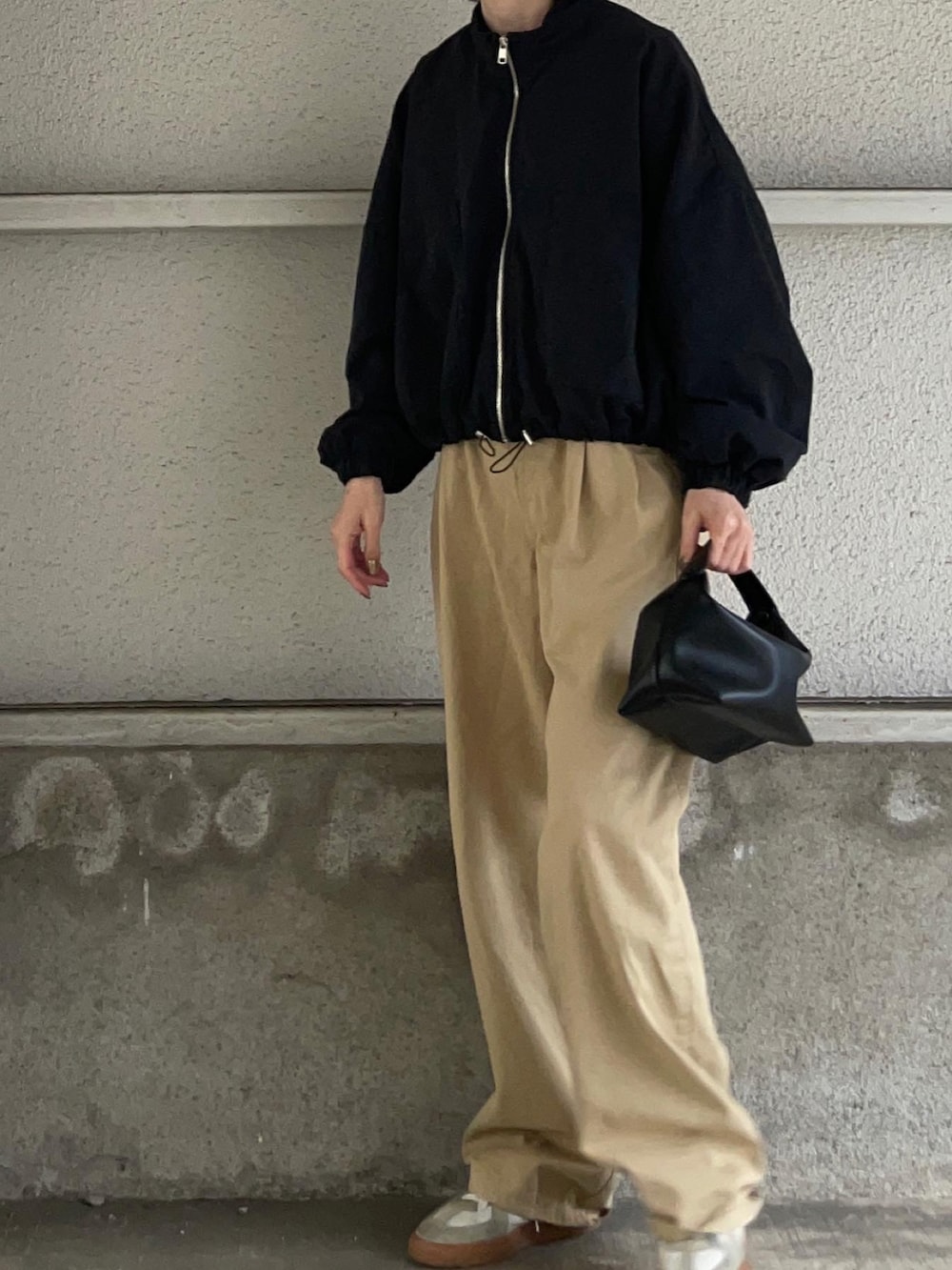 ブラック系のブルゾン、ベージュ系のその他パンツ、ホワイト系のスニーカーを着用したレディースの春コーディネートの2枚目の写真