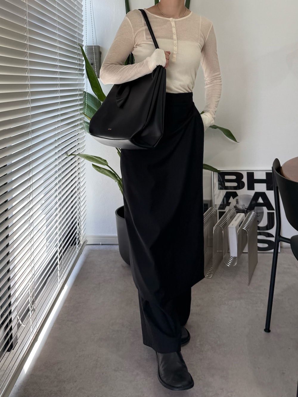 ブラック系のトートバッグ、ブラック系のスリッポン、ベージュ系のトップスを着用したレディースの秋コーディネートの2枚目の写真