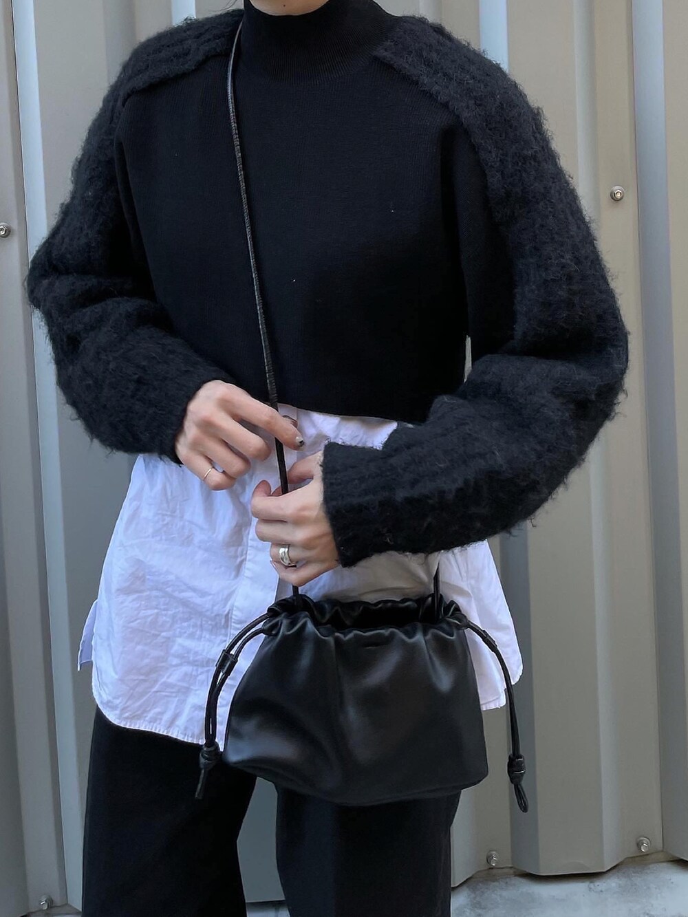 ブラック系のニット/セーター、ブラック系のハンドバッグ、ブラック系のパンツを着用したレディースの冬コーディネートの2枚目の写真