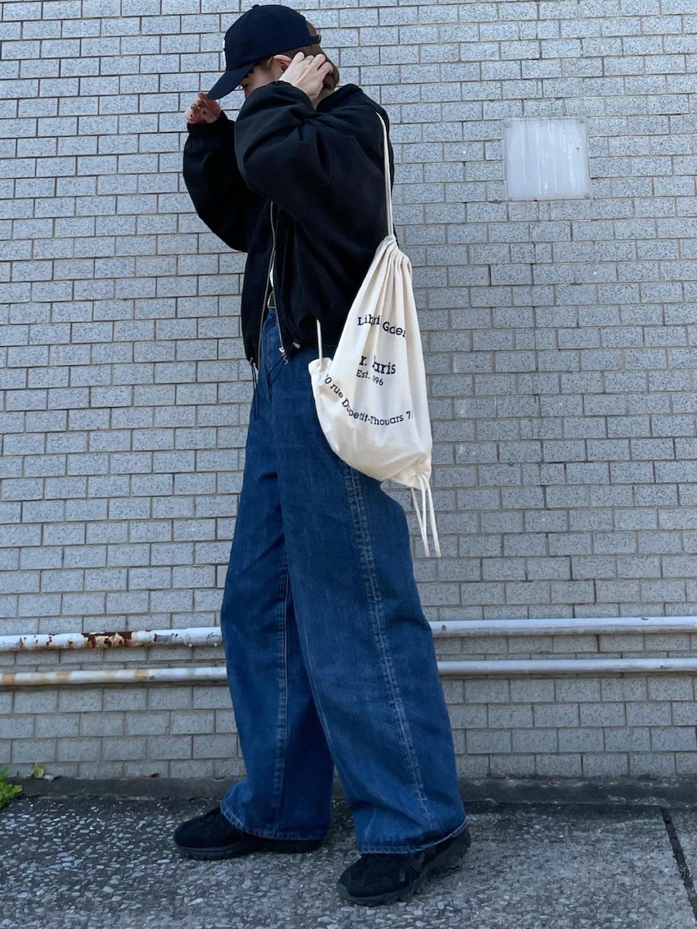 ブラック系のブルゾン、ブルー系のデニムパンツ、ブラック系のスニーカーを着用したレディースの春コーディネートの3枚目の写真