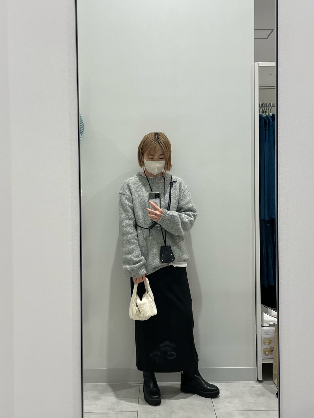 グレー系のニット/セーター、ブラック系のスカート、ブラック系のブーツを着用したレディースの冬コーディネートの2枚目の写真