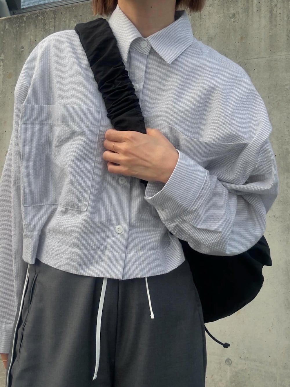 ブルー系のシャツ/ブラウス、グレー系のその他パンツ、ブラック系のショルダーバッグを着用したレディースの春コーディネートの4枚目の写真