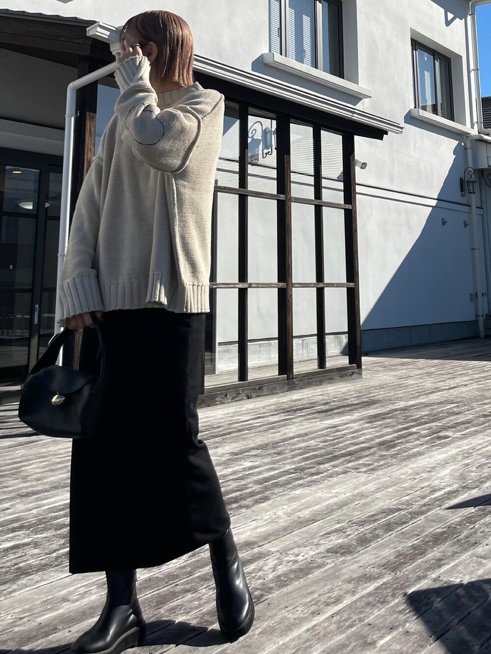 ベージュ系のニット/セーター、ブラック系のスカート、ブラック系のブーツを着用したレディースの秋コーディネートの3枚目の写真