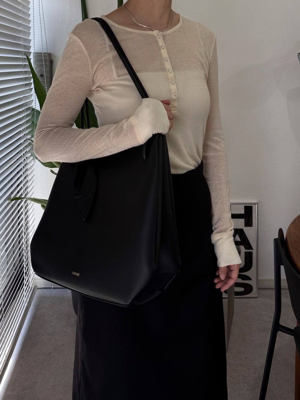 ブラック系のトートバッグ、ブラック系のスリッポン、ベージュ系のトップスを着用したレディースの秋コーディネートの3枚目の写真