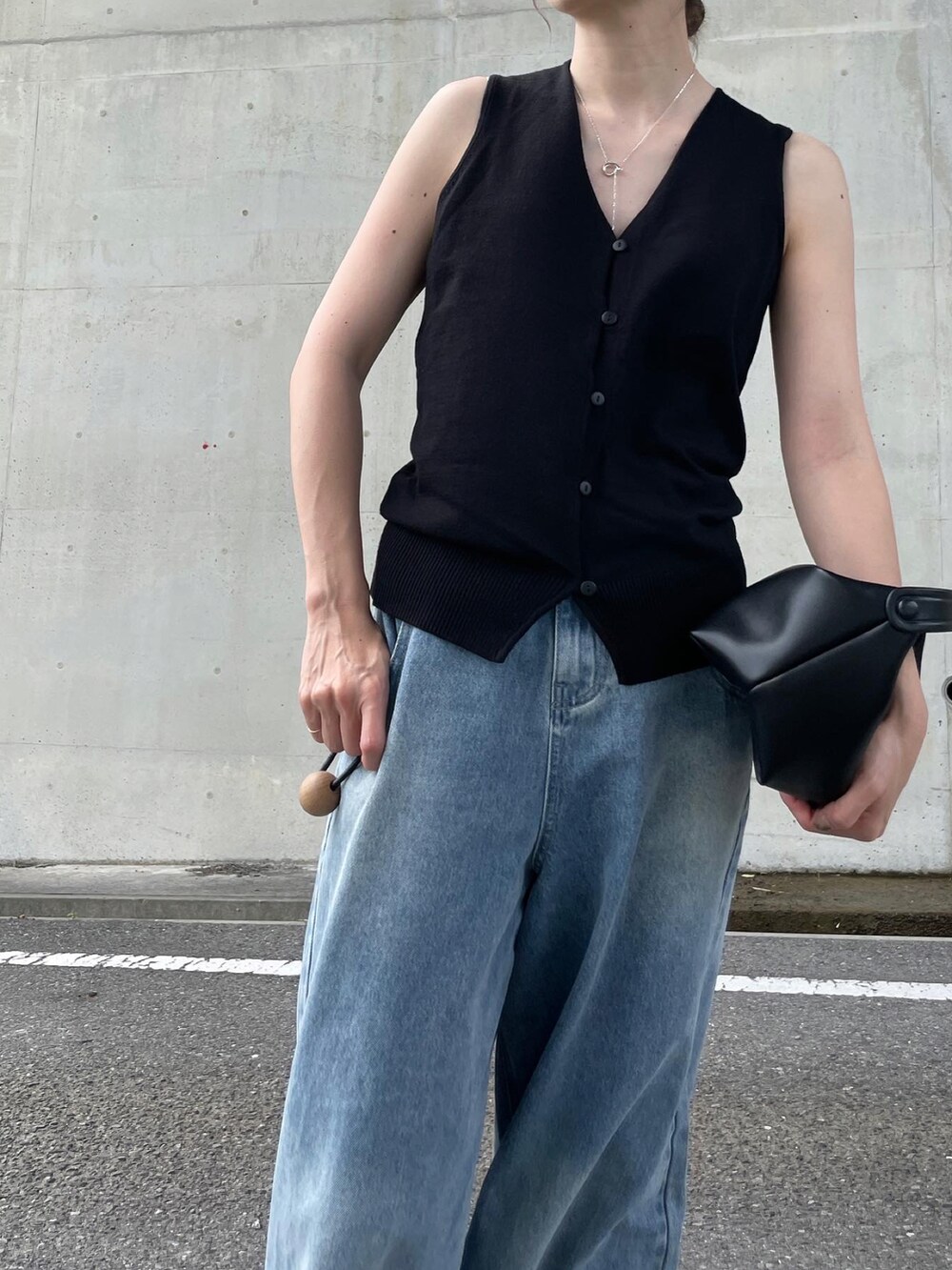 ブラック系のスニーカー、ブラック系のベスト、ブラック系のバッグを着用したレディースの夏コーディネートの2枚目の写真