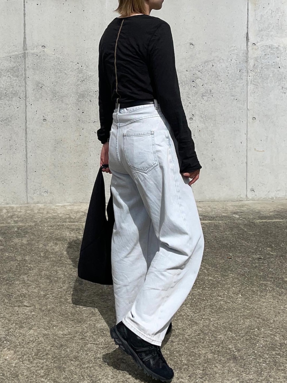 ブラック系のTシャツ/カットソー、ブルー系のデニムパンツ、ブラック系のスニーカーを着用したレディースの秋コーディネートの2枚目の写真