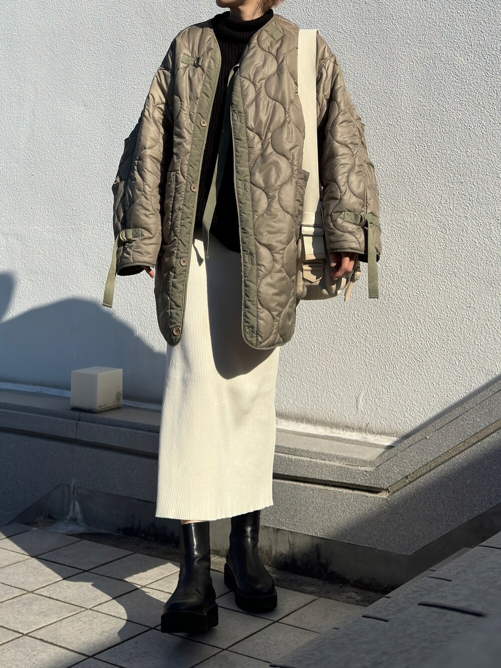 グリーン系のその他アウター、ブラック系のニット/セーター、ホワイト系のスカートを着用したレディースの冬コーディネートの2枚目の写真