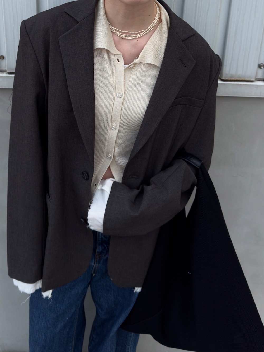 ホワイト系のカーディガン/ボレロ、グレー系のテーラードジャケット、ブルー系のデニムパンツを着用したレディースの春コーディネートの2枚目の写真