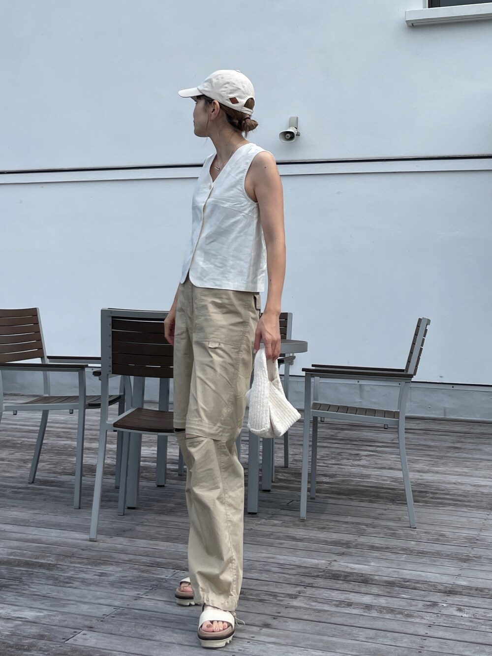 ホワイト系のベスト、ベージュ系のチノパンツ、ホワイト系のサンダルを着用したレディースの夏コーディネートの2枚目の写真