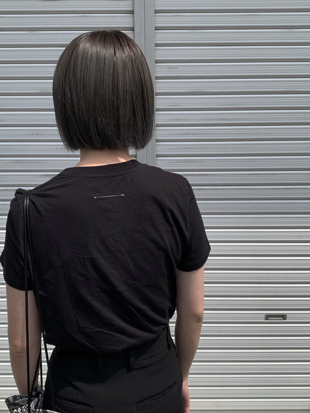 ブラック系のTシャツ/カットソー、ブラック系のスラックス、ブラック系のサンダルを着用したレディースの夏コーディネートの3枚目の写真