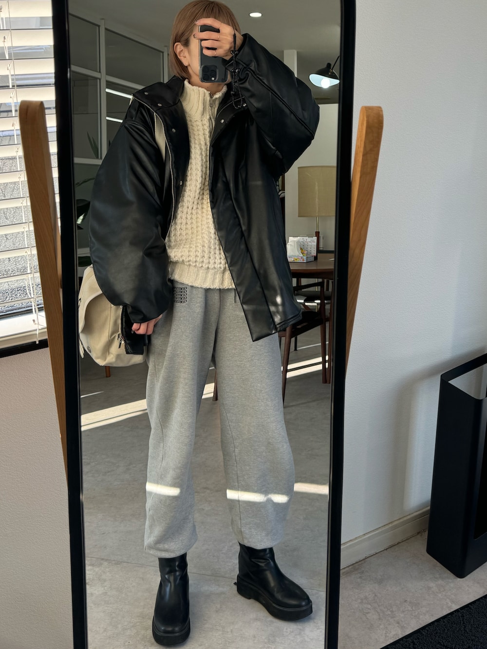 ブラック系のその他アウター、ホワイト系のニット/セーター、グレー系のスウェットパンツを着用したレディースの冬コーディネートの2枚目の写真