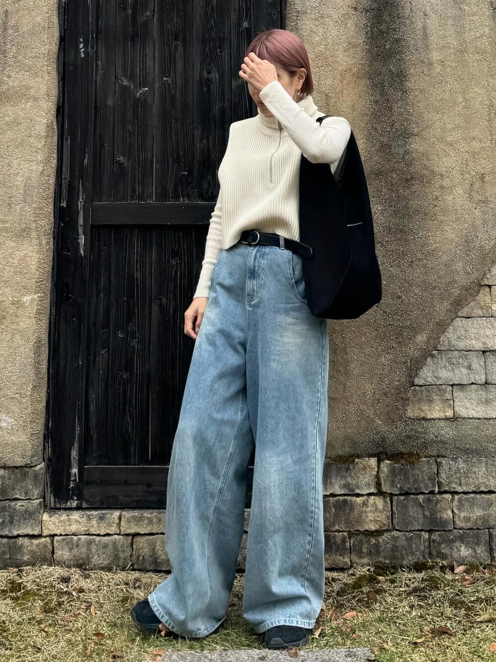 ホワイト系のベスト、ブラック系のトートバッグ、ブルー系のデニムパンツを着用したレディースの秋コーディネートの3枚目の写真